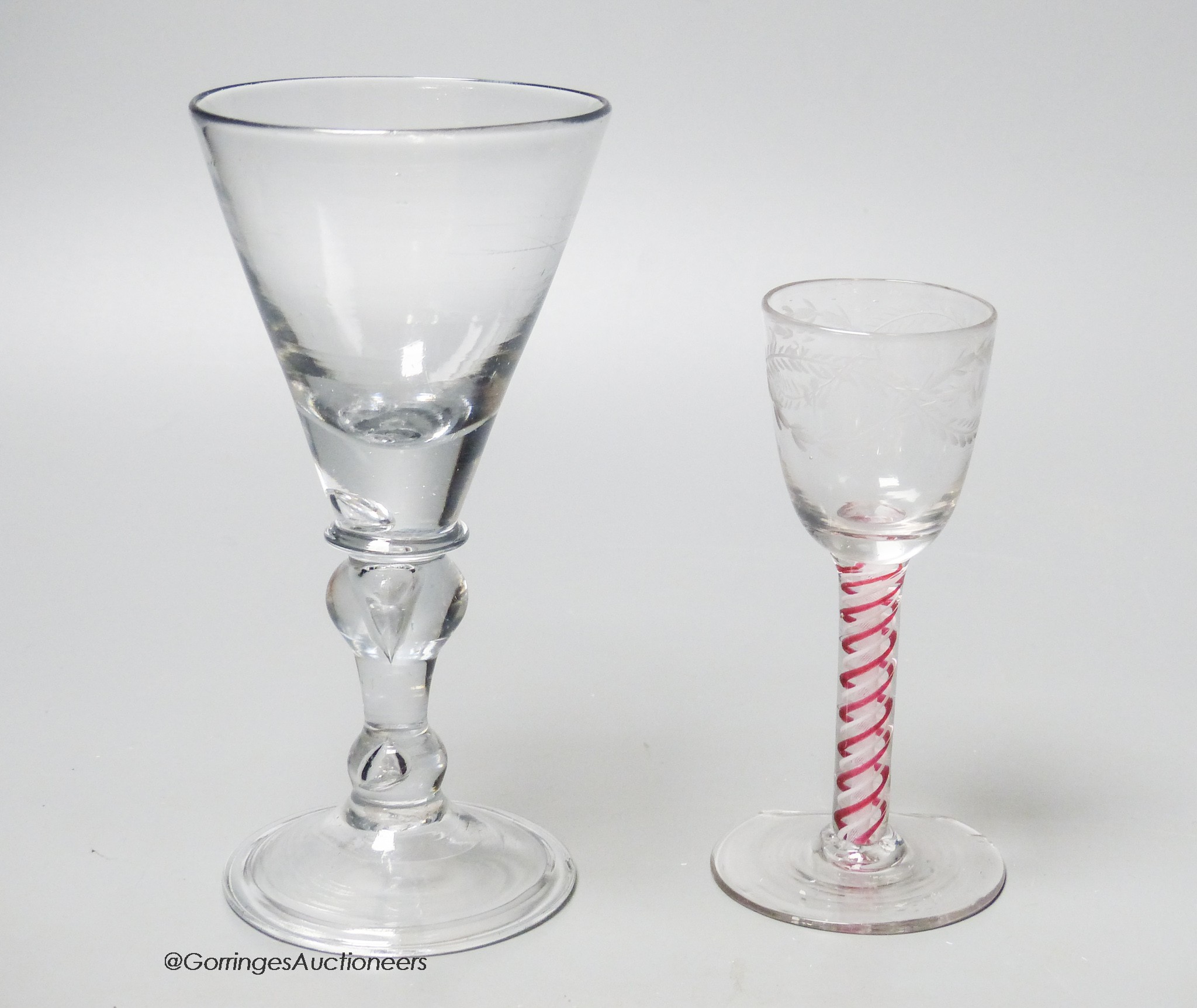 An early 18th century light baluster wine glass and an English red and white colour twist cordial glass, tallest 17.5cm